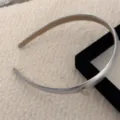 Elegante cerchietto sottile argento metallizzato da donna su sfondo di tessuto bianco - Argento