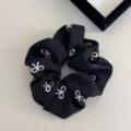 Scrunchie in tessuto nero con ricami di fiocchi bianchi per un look capelli elegante. - Elastico per capelli / Nero