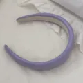 Detailed shot of a purple padded leather headband on white ruffled fabric. - Purple