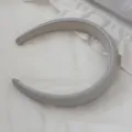 Detailed macro view of a grey padded leather headband resting on soft white fabric - Gray