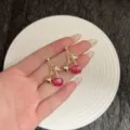 Macro view of elegant sweet cherry stud earrings with glitter red and gold finish. - Round Cherry Style (E4812) / Gold Red