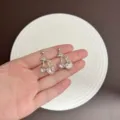 Elegant silver cherry stud earrings with pink heart crystals, displayed on palm. - Heart Cherry Style (E4811) / Silver Pink