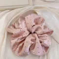 Gros plan d'un chouchou en satin rose à pois noirs avec des froufrous très délicats. - Chouchou / Rose à Pois