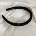 Gros plan d'un serre-tête en satin noir à pois blancs sur un fond de tissu texturé élégant - Serre-tête / Pois Noir