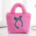 Detailopname van de zachte roze pluche handtas met een blauw geborduurd strikje. - Bow rose