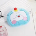 Primo piano di un simpatico portamonete in peluche blu con dettaglio viso ricamato - Blu
