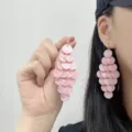 Close-up of pink layered disc tassel earrings held by hand and worn on the ear - Stud Earrings / Pink