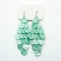 Detail view of mint green pearlescent disc tiered dangling earrings for vacation style. - Hook Style / Mint Green