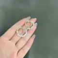 Dettaglio macro di eleganti orecchini dorati con perle bianche e cristalli lucenti. - Stile Bottone Perla Strass Doppio Cerchio (E1669) / Oro