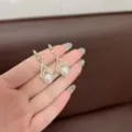Vista dettagliata di orecchini geometrici dorati con strass e perle bianche. - Stile Perla Rombo Geometrico (E1833) / Bianco