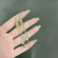 Primo piano di orecchini a foglia dorati con strass e pietre occhio di gatto - Stile Nappina Lunga Foglia Svuotata (E1659) / Oro