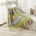 Soft yellow and grey jacquard throw blanket with decorative tassels draped over a sofa - Great Wall Lemon Yellow Gray