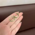 Vintage green enamel hoop earrings in gold-tone finish held in hand for detail. - Avocado Green
