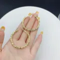 Elegant large gold-toned geometric textured hoop earrings held in hand for scale - Textured Geometric Hoop (E2730) / 4cm / Gold