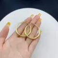 Fashionable large gold-tone smooth circular hoop earrings for women displayed in hand - Small Round (E0517) / 3cm / Gold