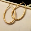 Macro view of minimalist matte gold oval hoop earrings with a textured finish. - Large (E4219) / 4.4cm/6.4cm / Matte Gold