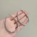 Minimalist large silver-toned geometric oval hoop earrings held in hand for scale - Large (E4219) / 4.4cm/6.4cm / Silver