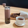 Detail shot of a manual coffee grinder with wood grain finish placed on a wooden table - Dark Wood Grain