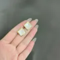 Primo piano dei piccoli orecchini a perno quadrati in pietra occhio di gatto dorati - Stile Geometrico Pietra Occhio di Gatto Piramide (E1742) / Oro