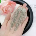 Detailed view of elegant silver rhinestone tassel drop earrings held in a hand - E1595 (10cm) / Silver