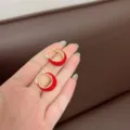 Close-up of red enamel U-shaped hoop earrings with gold-tone finish on hand. - U-Shaped Ear Buckle / Gold Bright Red