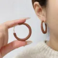 Detailed close-up of retro brown leather wrapped large hoop earrings worn on a model's ear - 4cm / Solid Brown