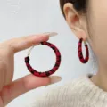 Close-up of red and black leopard print leather braided hoop earrings on ear and hand. - 4cm / Red + Black