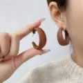 Chic macro detail of textured Ankara red C-shaped hoop earrings worn by a model - C-Shape Earrings Style (E4424) / One Size / Solid Coffee