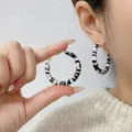 Detailed close-up of vintage zebra pattern wrapped leather hoop earrings on model - 4cm / White and Black