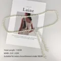 Detailed shot of an elegant pearl waist chain with a sparkling rhinestone flower clasp - Clover / 110cm