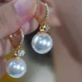 Close-up of elegant gold hoop earrings with sparkling diamonds and large white pearls - Heavy Craft Rhinestone White Pearl Style (E4495)