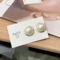 Elegante übergroße Perlenohrstecker mit gedrehtem Goldkreisrahmen auf Displaykarte - Gold Weiß