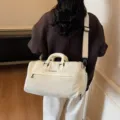 Cream white travel duffel bag with separate shoe compartment and adjustable shoulder strap. - White