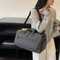 Black and white plaid travel duffel bag with adjustable shoulder strap for sports and gym use. - Black