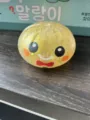 Gros plan d'un jouet à presser en forme de brioche jaune pailletée avec un visage souriant. - Bonhomme en pain d’épice / 1 Pièce