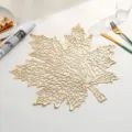 Close-up of a golden maple leaf hollowed PVC heat-resistant placemat for dining table decoration - H款 (镂空枫叶) / Gold
