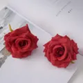 Detailed macro view of two red silk artificial rose flower heads on an open white book. - Bright Red