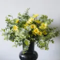 Lifelike artificial yellow daisy and green eucalyptus bouquet in a black decorative vase - Yellow