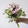Artificial pink daisy and eucalyptus leaf bouquet held by hand for floral decor - Pink