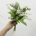 Künstlicher Eukalyptus- und Maiglöckchenstrauß für die Inneneinrichtung in der Hand - Maiglöckchen Strauß