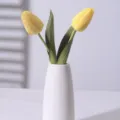 Two yellow moisturizing artificial tulips presented in a minimalist white ceramic vase - Yellow