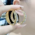 Detailed macro view of elegant gold hoop earrings with sparkling crystal accents being held - Pave Rhinestone Large Hoop Style (E3590) / Gold