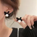 Detailed close-up showing the elegant black velvet bow earrings with white pearls - Velvet Bowknot Artificial Pearl Stud Earrings (E3617) / Black