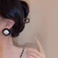 Detailed view of an elegant black square earring with a white pearl on a model's ear - Black and White Square Pearl Stud Earrings (E3638) / Black