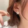 Golden starfish stud earring with pearls variant view on Asian model's ear profile - Pearl Starfish Style (E2952) / Gold White