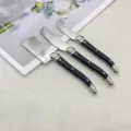 Close-up detail of 3-piece stainless steel cheese knife and butter spreader set with black handles - 3-Piece Cheese Knife Set