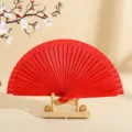 Elegante abanico plegable de madera roja sobre soporte minimalista para decoración - Rojo