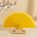 Elegante abanico plegable español de madera amarillo con soporte de madera minimalista. - Amarillo