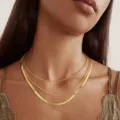 Elegante dettaglio di una collana a tre strati in oro con catene su una modella femminile - Combinazione di Catena ad Anelli Fini e Serpente / Oro