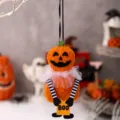 Close-up of a fuzzy plush Halloween pumpkin ornament with white mesh collar and BOO sign - Pumpkin Doll Hanging